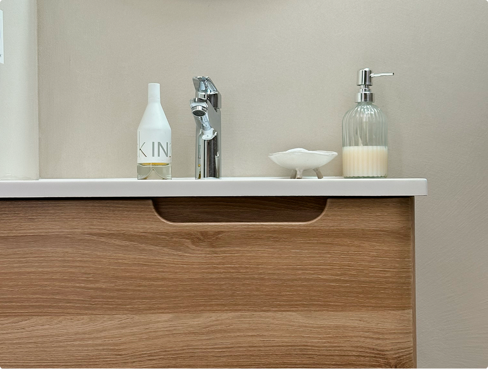 Detail eines Gästebads von X²O Badezimmer mit schwebendem Waschtisch in Eichenoptik, weißem Waschbecken, Chromarmatur und Pflegeprodukten.