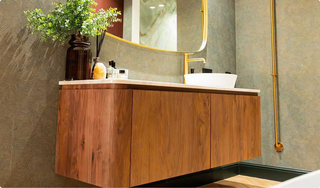 Deze foto laat een prachtig x²o badkamers detail zien: een groot ovaal vrijstaand bad met een gouden kraan en een handdoek. Ernaast staan grote groene planten en de vloer heeft een warme houtlook die de luxe uitstraling versterkt.