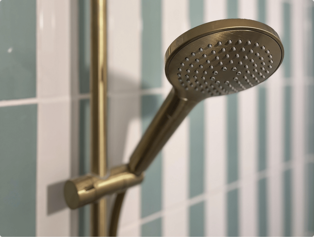 Bad-douche met gouden kraanwerk en verticale pastelgroene tegels, inclusief het vertrouwde badeendje – een creatie van x2o badkamers.