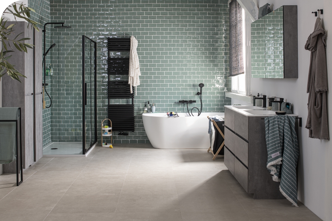 Salle de bain moderne avec carrelage vert, baignoire autoportante et paroi de douche en verre.