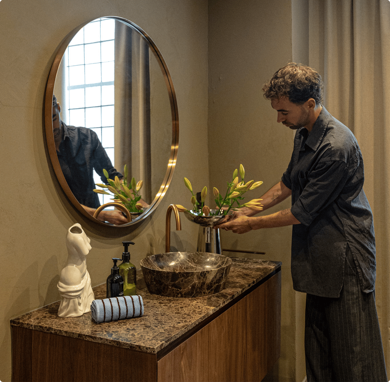 Daan Alferink schikt bloemen aan zijn marmeren wastafel met gouden kraan.