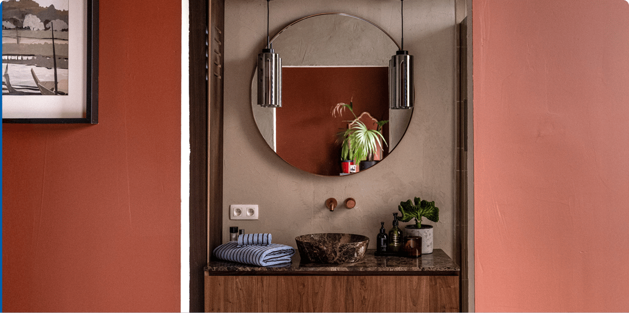 Marmeren waskom op houten meubel onder ronde spiegel met verlichting.