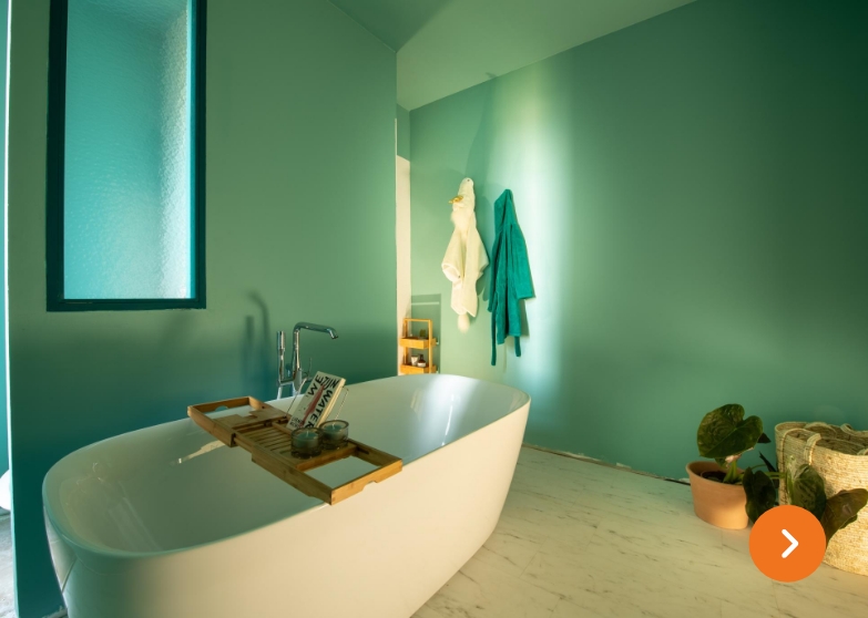 Minimalistisches Badezimmer mit türkisfarbenen Wänden, freistehender Badewanne und hölzernem Badewannenbrett