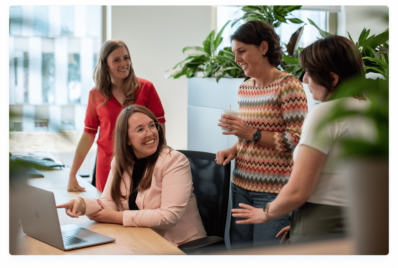 Lachende collega’s overleggen aan bureau in het kantoor van X2O badkamers.