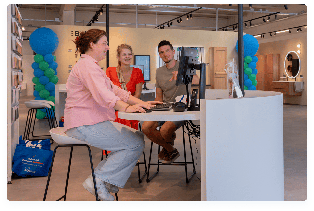 Verkoopster adviseert een koppel in de X2O badkamers showroom tijdens een persoonlijk adviesgesprek.