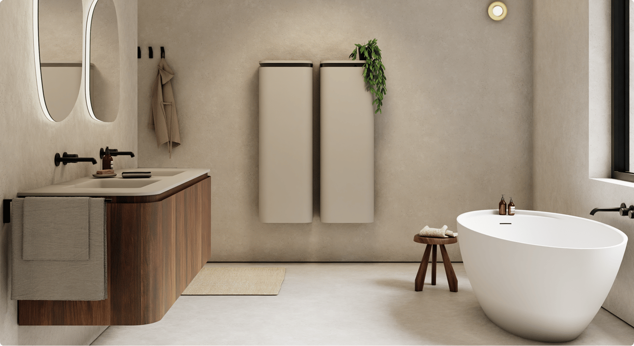 Minimalistische x²o badkamers met strakke lijnen en warme aardetinten. Links een houten meubel met dubbele wastafel, matzwarte kranen en verlichte spiegels. Rechts een ovale vrijstaande badkuip met houten krukje en verzorgingsproducten ernaast.