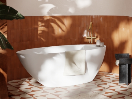  Badkuip met gouden kraan en tegels in warme kleuren.