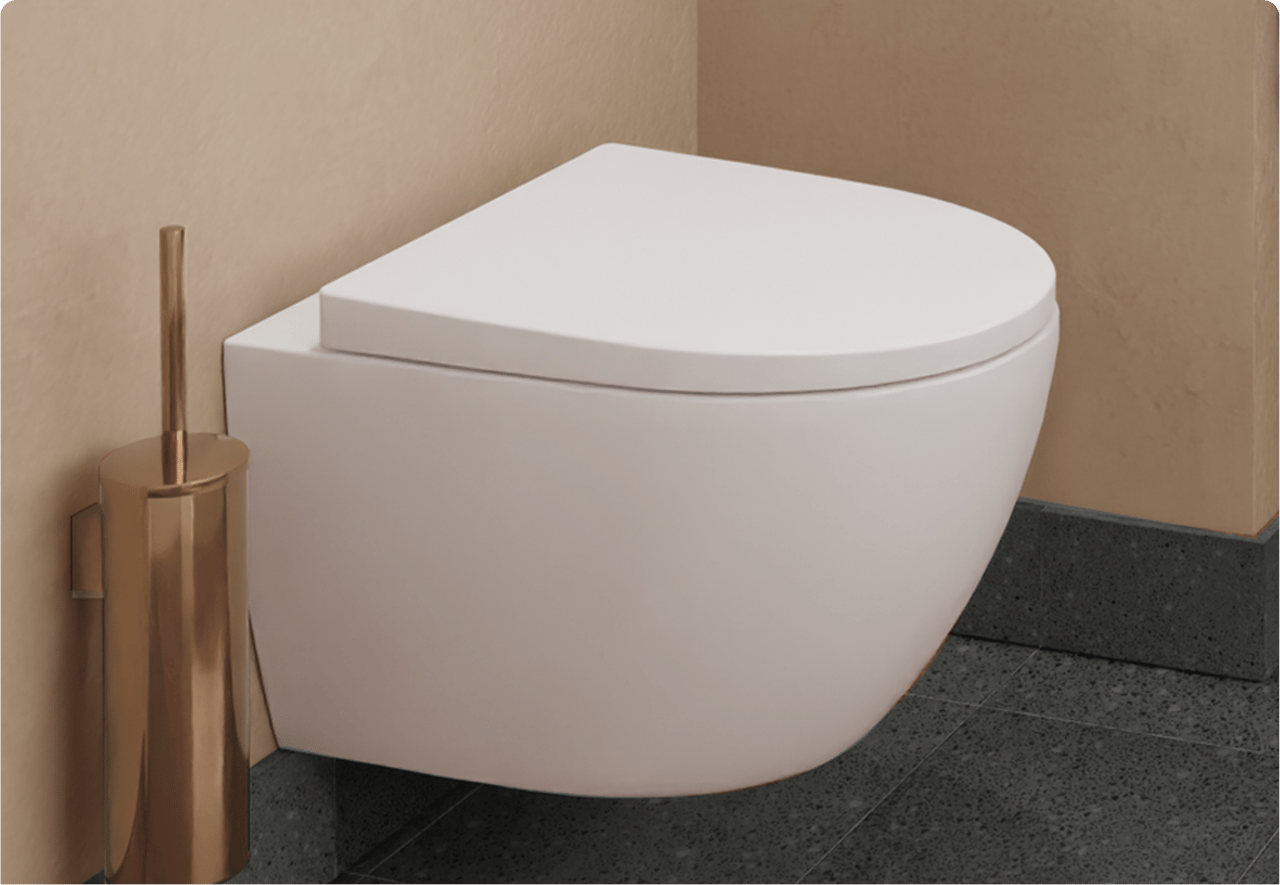Glanzend wit hangtoilet tegen een roodbruine wand, met een koperkleurige toiletborstel. Warme luxe van x²o badkamers.