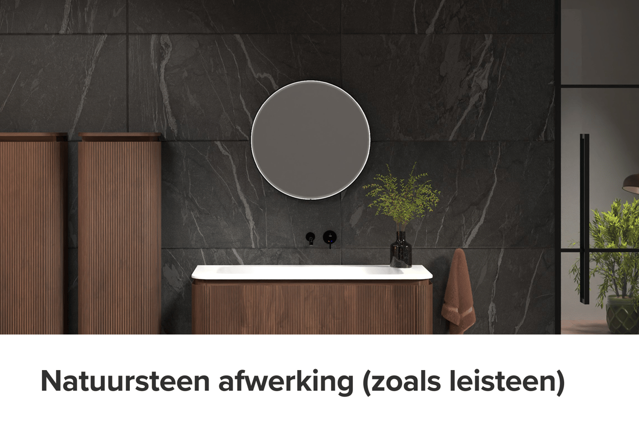 x²o badkamers meubel tegen een wand met natuursteenafwerking in leisteen-look. Rond verlicht spiegel, verticale houten kolomkasten en een zwart kraantje boven een wit werkblad benadrukken het luxe karakter.