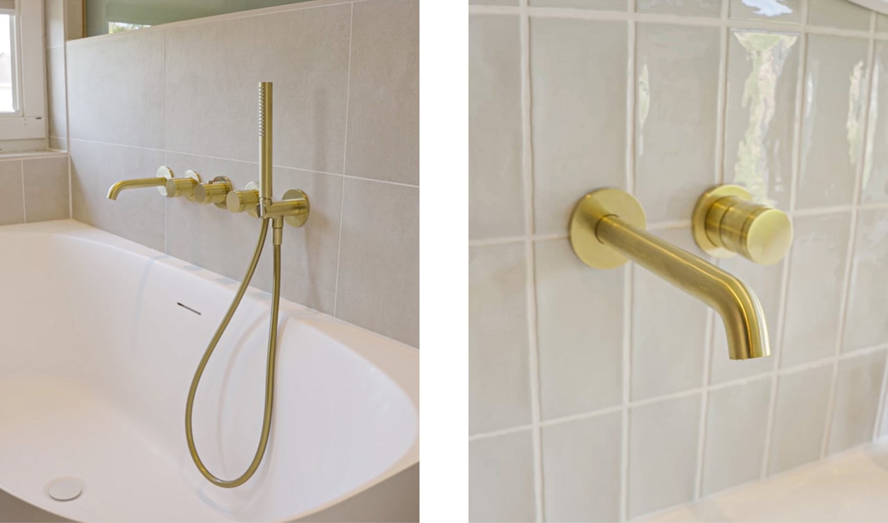 Goldene Wandarmatur und Handbrause über einer weißen Badewanne, angebracht an einer Wand mit matten, neutralen Fliesen. Design von x²o Bad.