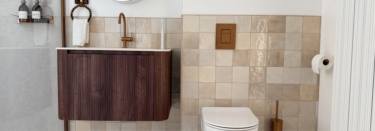 Detail van x²o badkamers meubel in walnootkleur met wastafel, spiegel en accessoires op beige tegelwand.