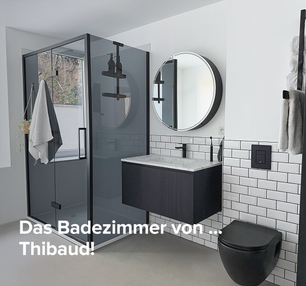 Badezimmer von x²o Bad mit Dusche, schwarzem Möbel und rundem Spiegel mit deutschem Text „Das Badezimmer von Thibaud“.