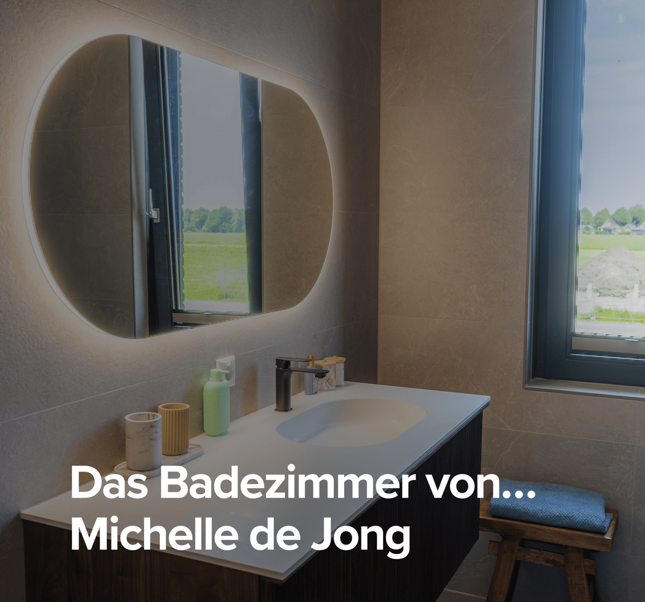 Überblick über das Badezimmer von Michelle de Jongg mit modernem Waschtisch, beleuchtetem Spiegel und Glasduschwand.