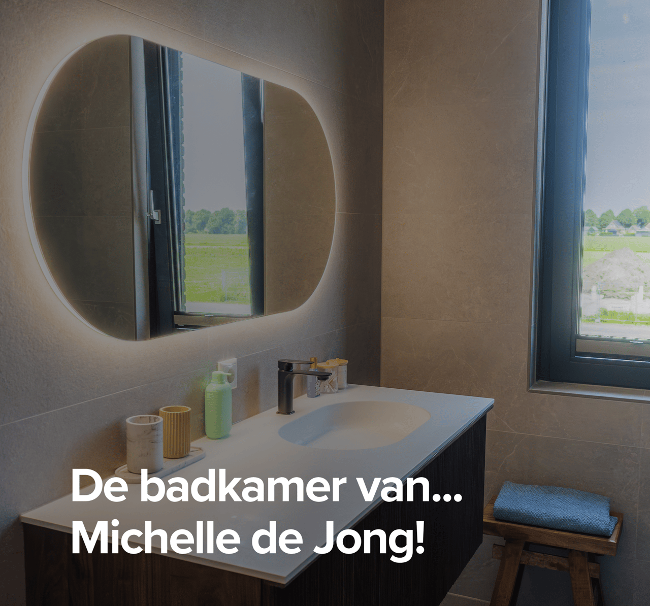 Overzicht van Michelle de Jongg’s badkamer met modern badkamermeubel, verlichte spiegel en glazen douchewand.