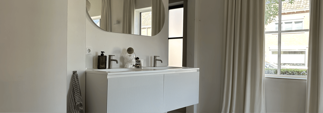Elegante badkamer van x²o badkamers met zwevend Balmani Fila badkamermeubel, grote organische spiegel en lichte neutrale kleuren.