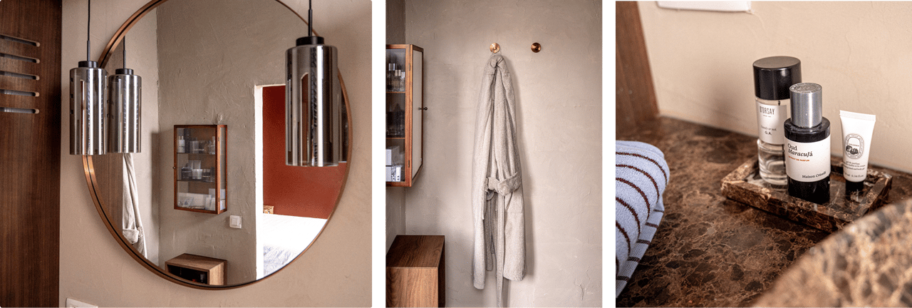 Moderne badkamer met ronde spiegel, stijlvolle hanglampen, opgehangen badjas en marmeren wastafelblad met verzorgingsproducten – X2O badkamers