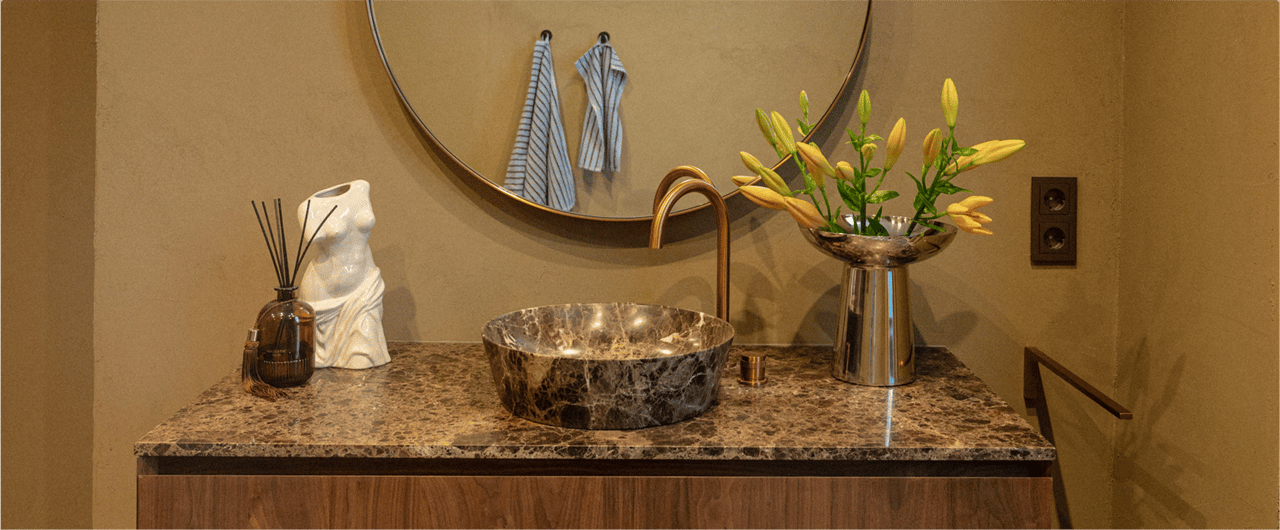 Waschbecken von X²O mit Spiegel, Marmorwaschschale und Blumen in Chromvase.