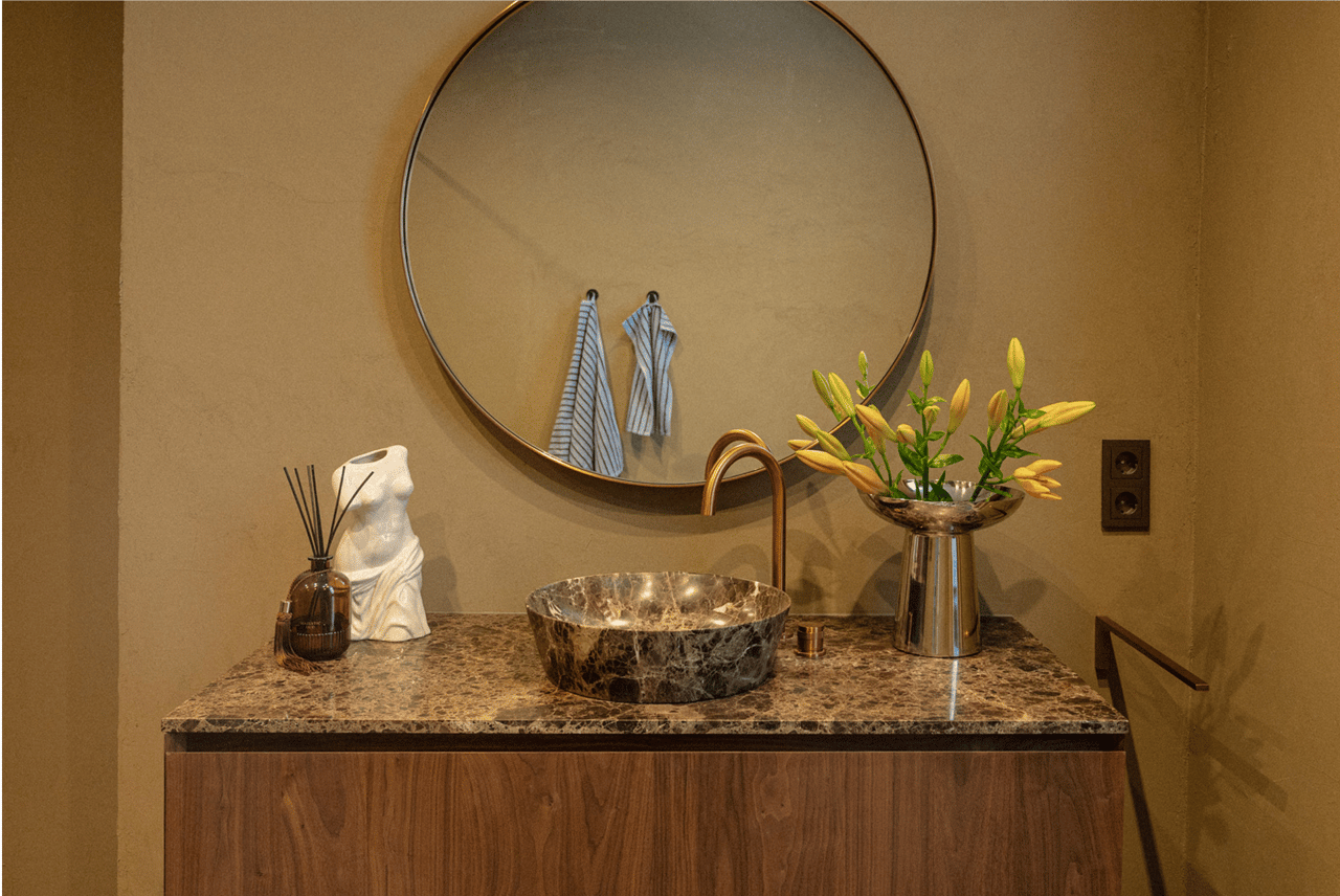 Waschbecken von X²O mit Spiegel, Marmorwaschschale und Blumen in Chromvase.