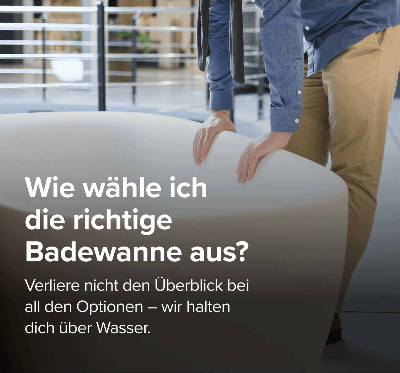 Auf diesem Bild von x²o badkamers siehst du einen Mann in beiger Hose und blauem Hemd, der eine große Designer-Badewanne von x²o badkamers in einem Showroom mit Industrie-Boden und anderen Badmodellen im Hintergrund begutachtet.