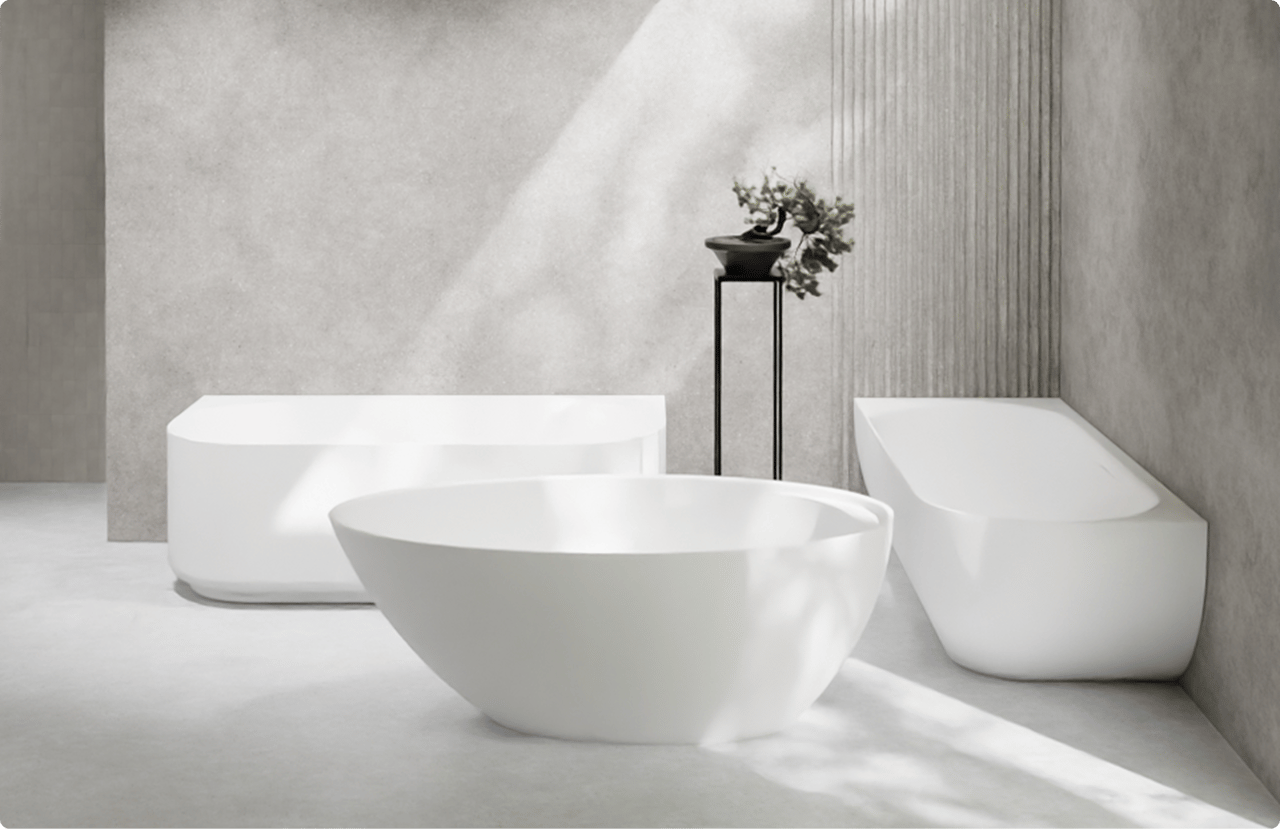 Op deze foto zie je drie verschillende vrijstaande baden in een minimalistische x²o badkamers setting. Vooraan staat een rond wit bad met zachte lijnen, links een rechthoekig bad met strakke hoeken en rechts een ovaal bad met een schuine rugleuning. De baden staan op een lichte betonnen vloer tegen grijze wanden met een subtiel verticaal reliëf. Een zwarte hoge plantenstandaard met een klein boompje maakt het serene design compleet.