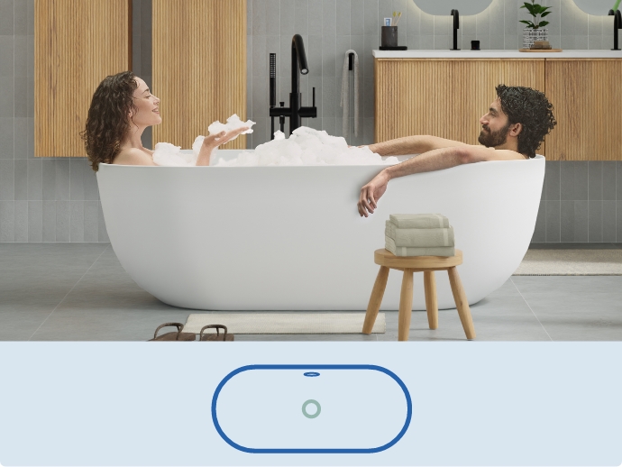 Twee mensen ontspannen in een witte vrijstaande badkuip, gevuld met schuim.