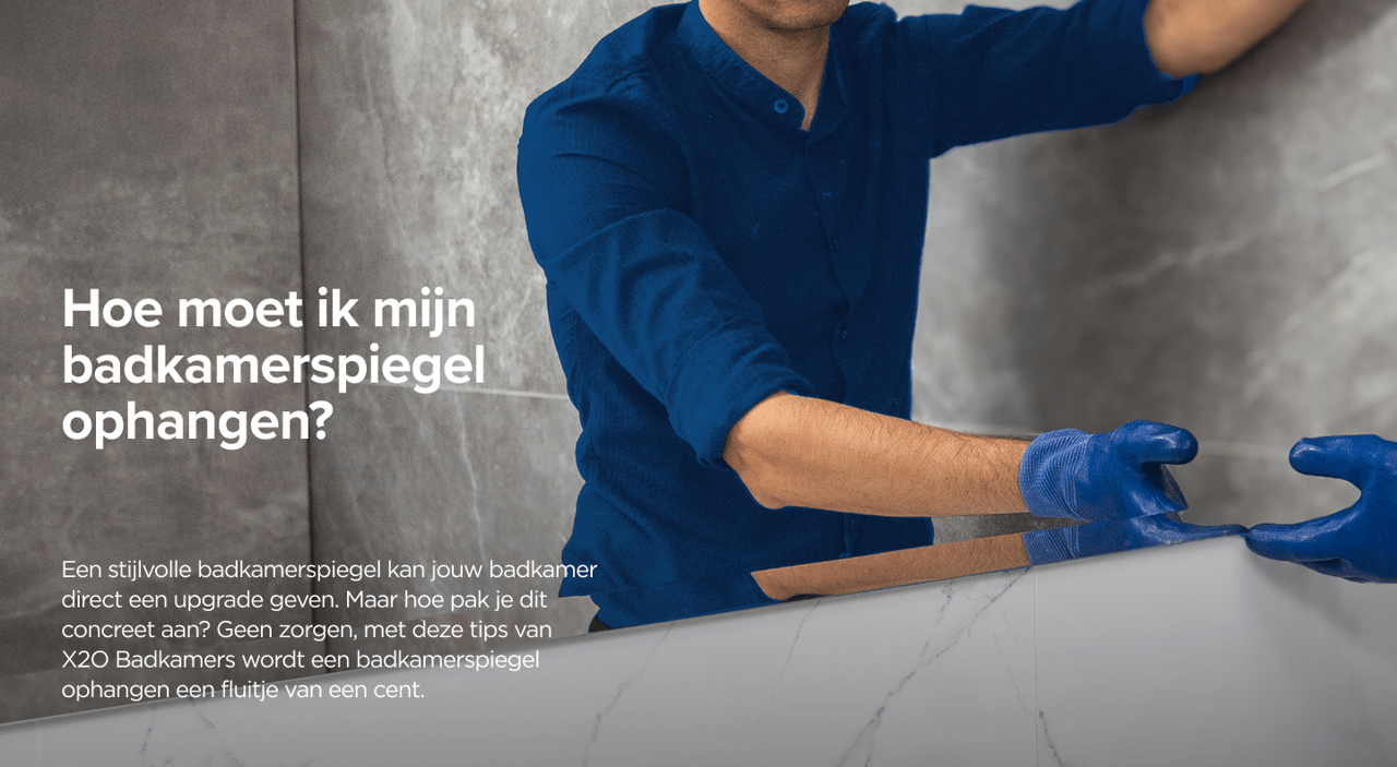 Monteur in blauwe werkkledij bevestigt een spiegel aan een badkamerwand met marmerlook – een praktische gids van x²o badkamers.