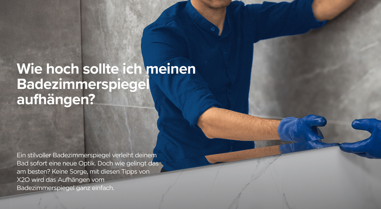 Ein Handwerker in blauer Arbeitskleidung befestigt einen Spiegel an einer Marmor-Optik-Wand im Bad – praktische Anleitung von x²o badkamers.