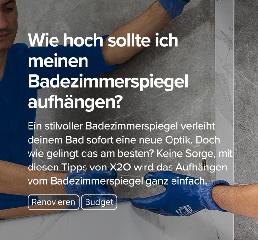 Ein Handwerker in blauer Arbeitskleidung befestigt einen Spiegel an einer Marmor-Optik-Wand im Bad – praktische Anleitung von x²o badkamers.