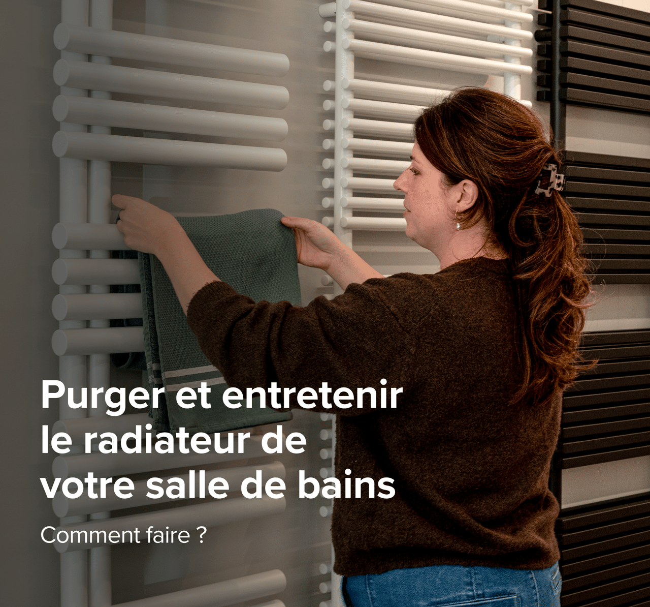 Femme accroche une serviette verte à un radiateur blanc entouré de modèles noirs dans un showroom X2O salles de bains.
