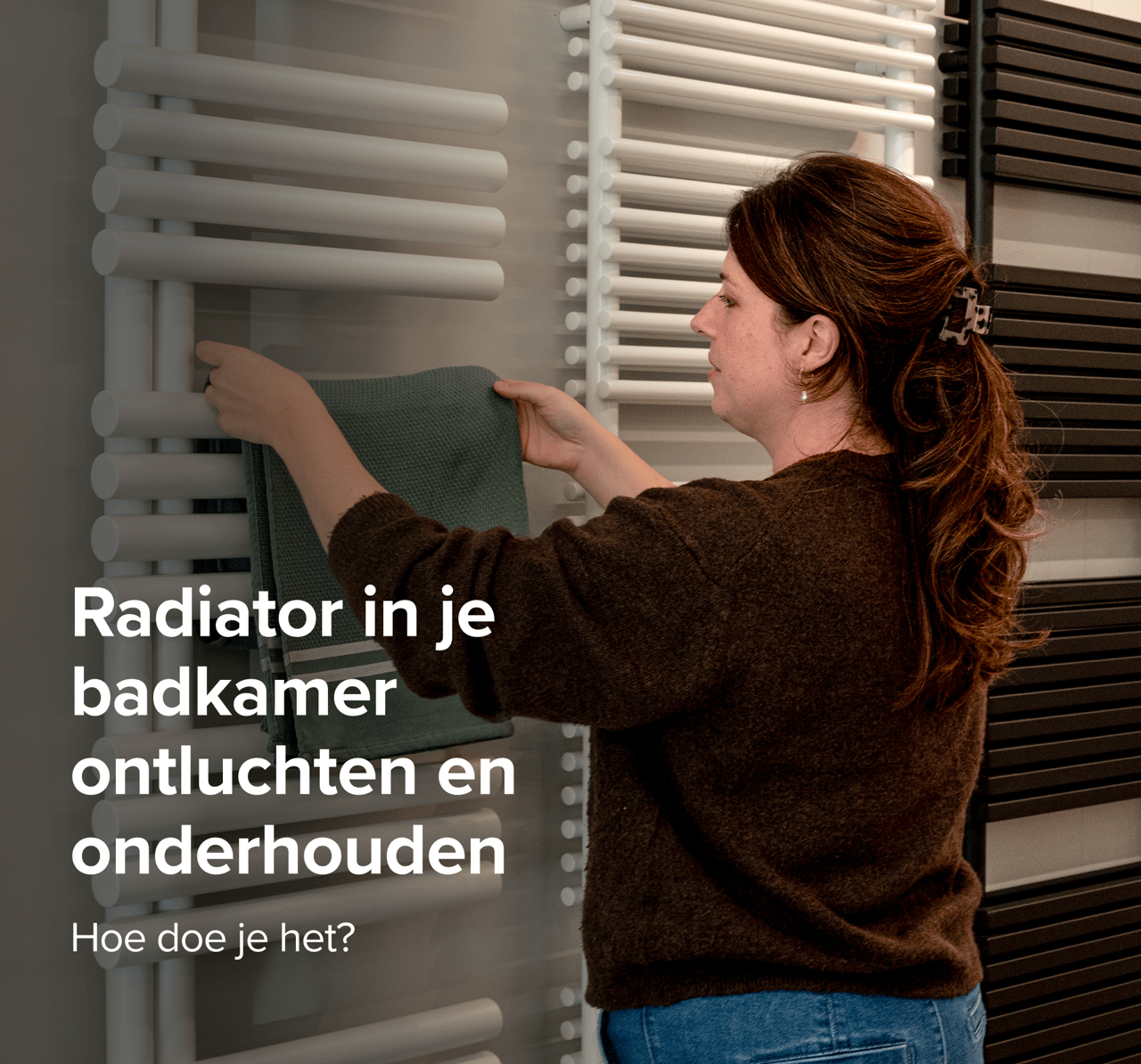 Vrouw hangt groene handdoek aan witte radiator tussen zwarte modellen in moderne X2O badkamers showroom.
