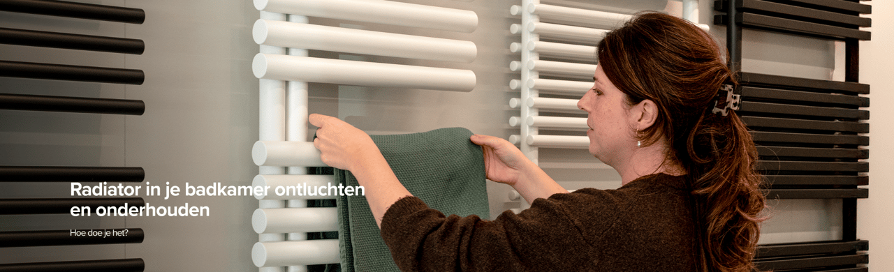 Vrouw hangt groene handdoek aan witte radiator tussen zwarte modellen in moderne X2O badkamers showroom.