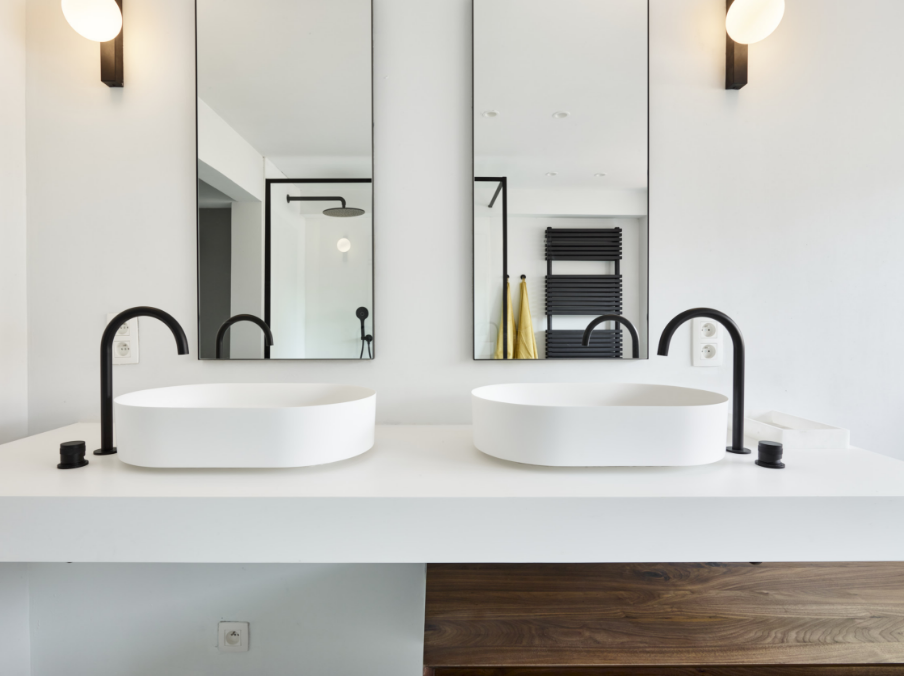 Ruime badkamer met ligbad, glazen douchewand en zwarte details.