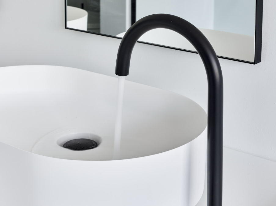 Close-up van een zwarte wastafelkraan met stromend water.