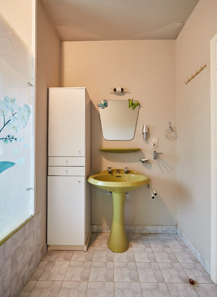 Retro badkamer met marmeren wastafelblad en geel sanitair.