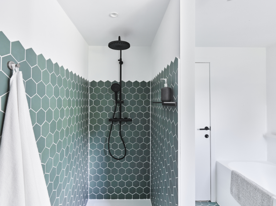 Schwarze Regendusche mit grünen sechseckigen Fliesen und Wasserstrahl.