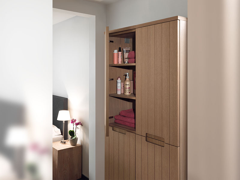 Houten badkamerkast met open deur, toont opbergplanken gevuld met handdoeken en verzorgingsproducten.