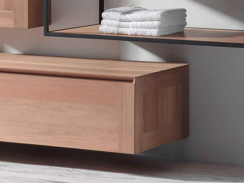 Close-up van een moderne badkamerplank met netjes gestapelde handdoeken op een houten plank en een houten lade eronder.