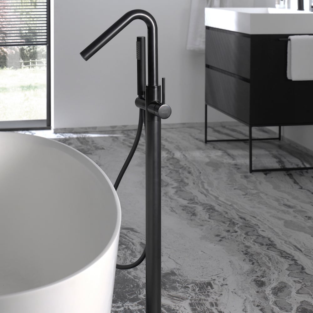 Vrijstaande zwarte badkraan met handdouche naast een modern wit ligbad, stijlvol en minimalistisch ontwerp.