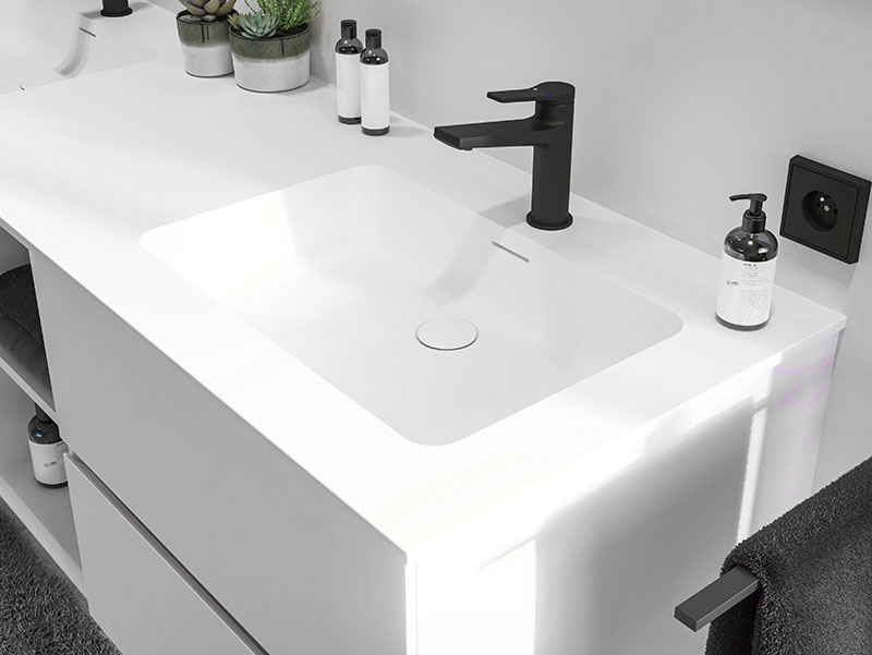 Witte wastafel met geïntegreerde wasbak en een matzwarte kraan op een moderne badkamerkast.