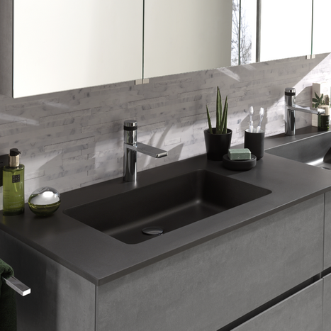 Modernes Waschbecken aus dunkler Keramik mit passendem Badmöbel und Chromarmatur, stilvolles Design.