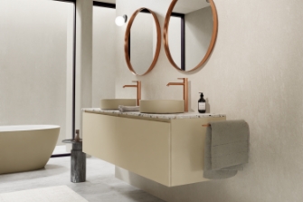 Luxe badkamer met zwevend beige wastafelmeubel, ronde spiegels en koperen kranen voor een elegante uitstraling.