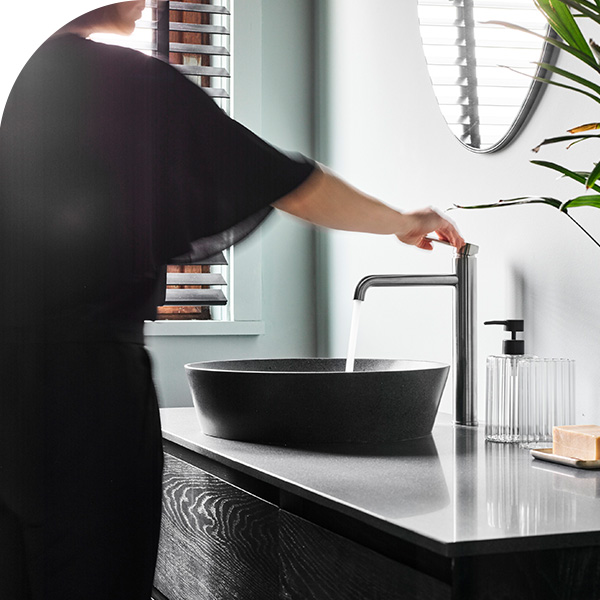 Modernes schwarzes Waschbecken mit Chromarmatur, minimalistisches Badmöbel und natürliches Licht.