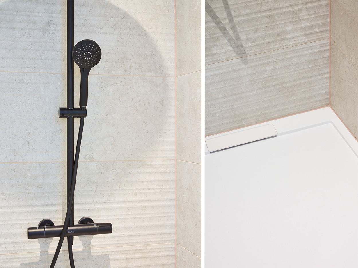 Douchette noire, robinet thermostatique et bac de douche blanc.