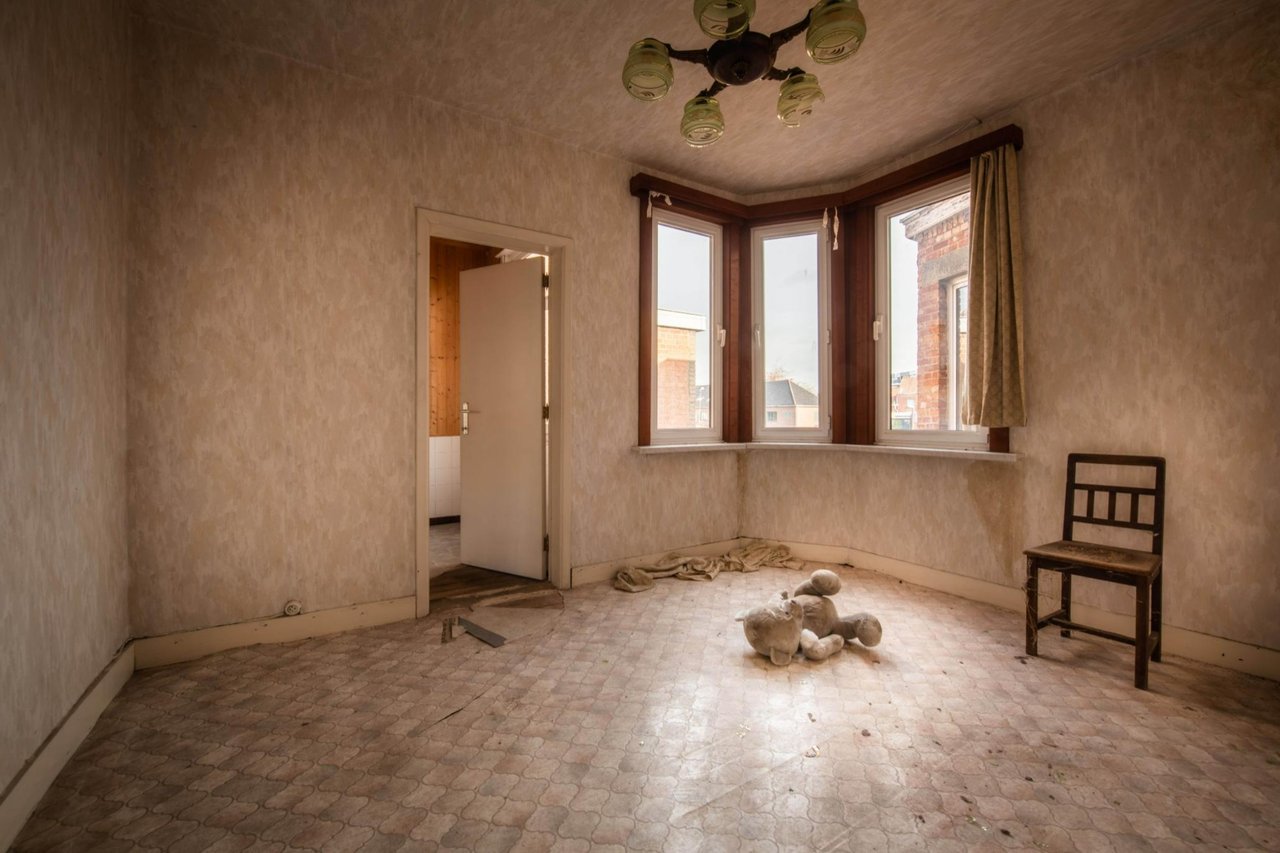 Verwaarloosde kamer met houten stoel, teddybeer op de vloer en verouderde muren