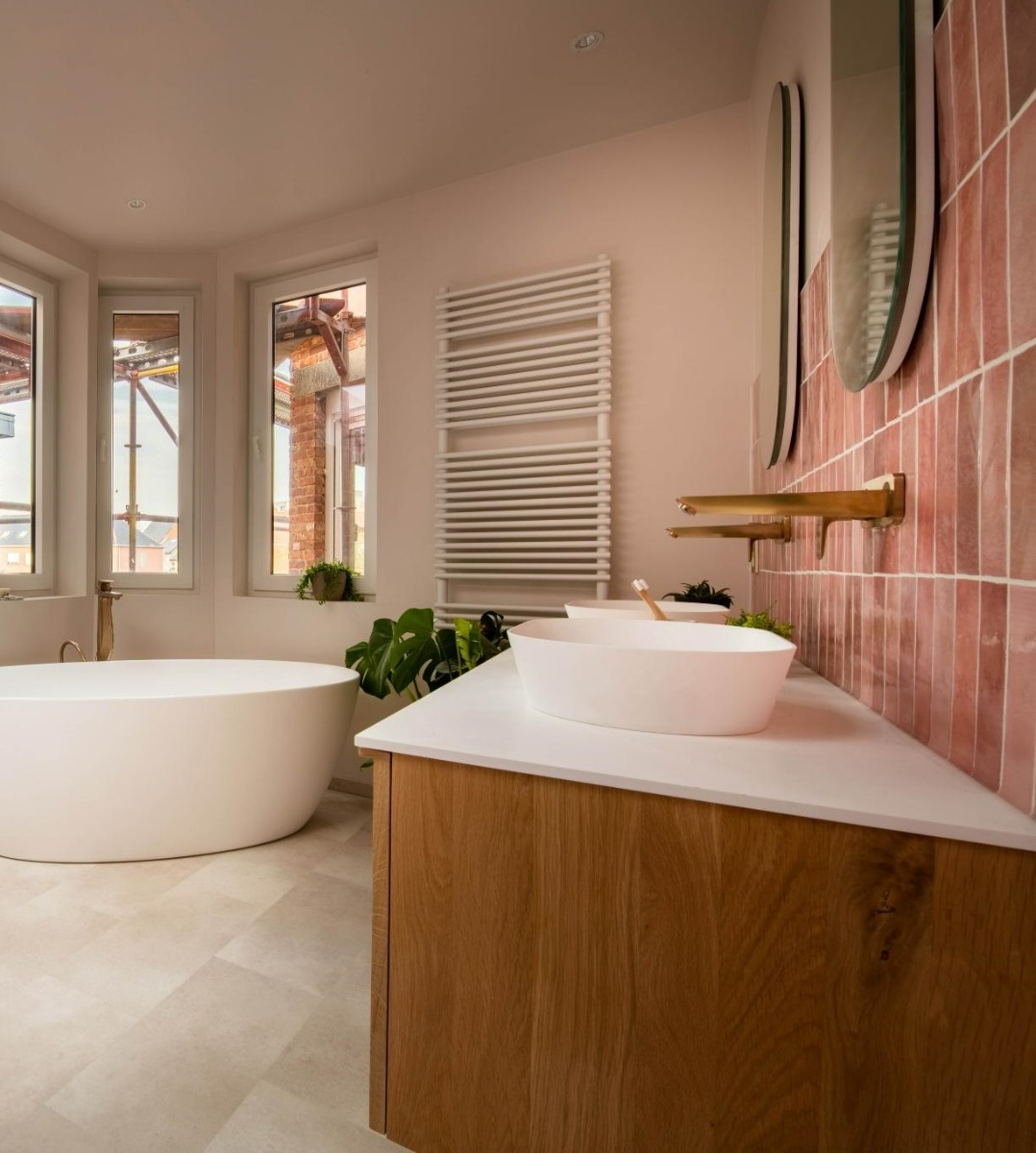 Moderne badkamer met vrijstaand bad, houten wastafelmeubel, gouden kranen en roze tegels