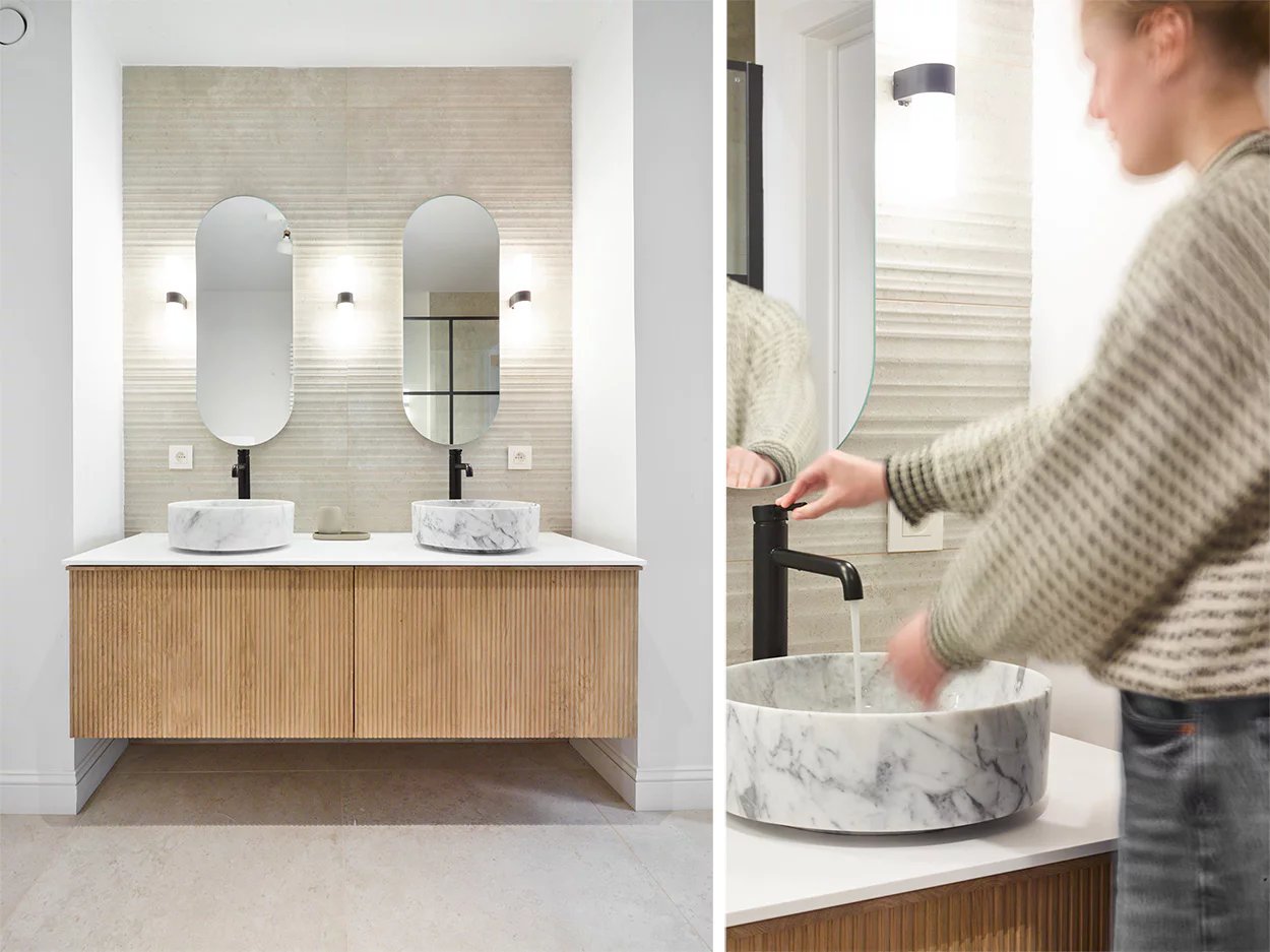 Salle de bain moderne avec un meuble vasque en bois et des lavabos en marbre, équipés de robinets noirs.