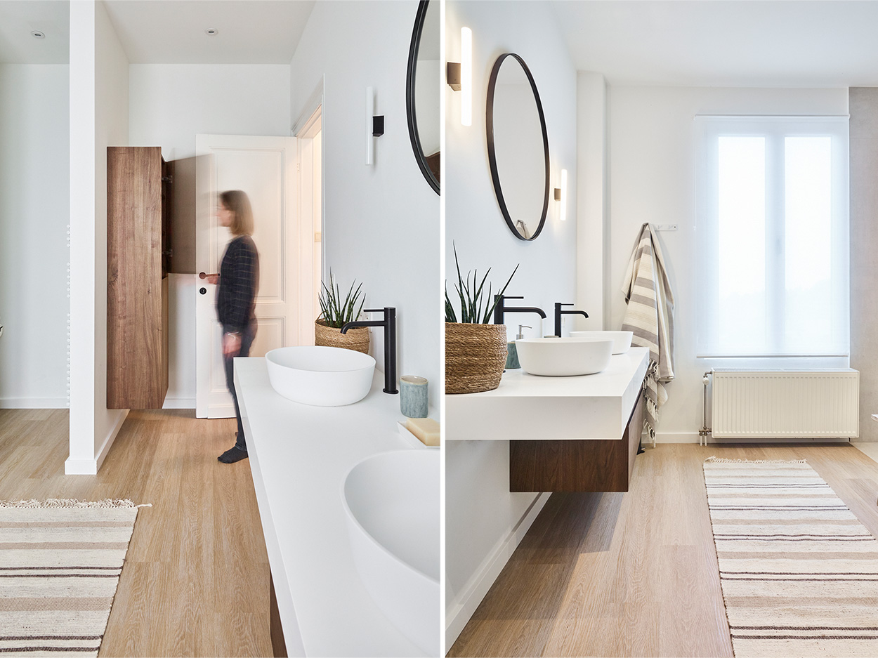 Salle de bain moderne avec deux lavabos, armoire en bois, grands miroirs ronds et un tapis au sol.