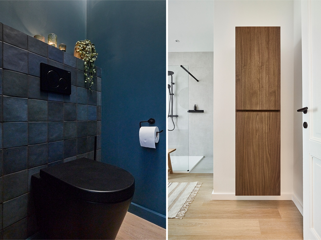 Toilet moderne noir, carrelage sombre et armoire en bois dans une salle de bain lumineuse.