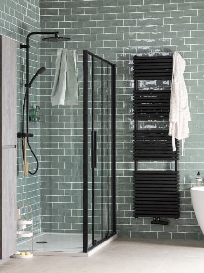 Dusche mit Glaswand, schwarzem Heizkörper und grünen Fliesen in einem modernen Badezimmer.