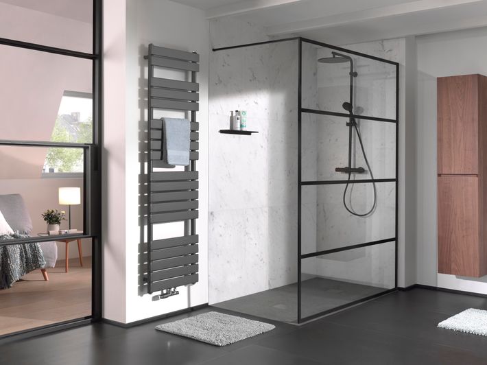 Moderne badkamer met glazen douchewand, radiator en een opbergkast.